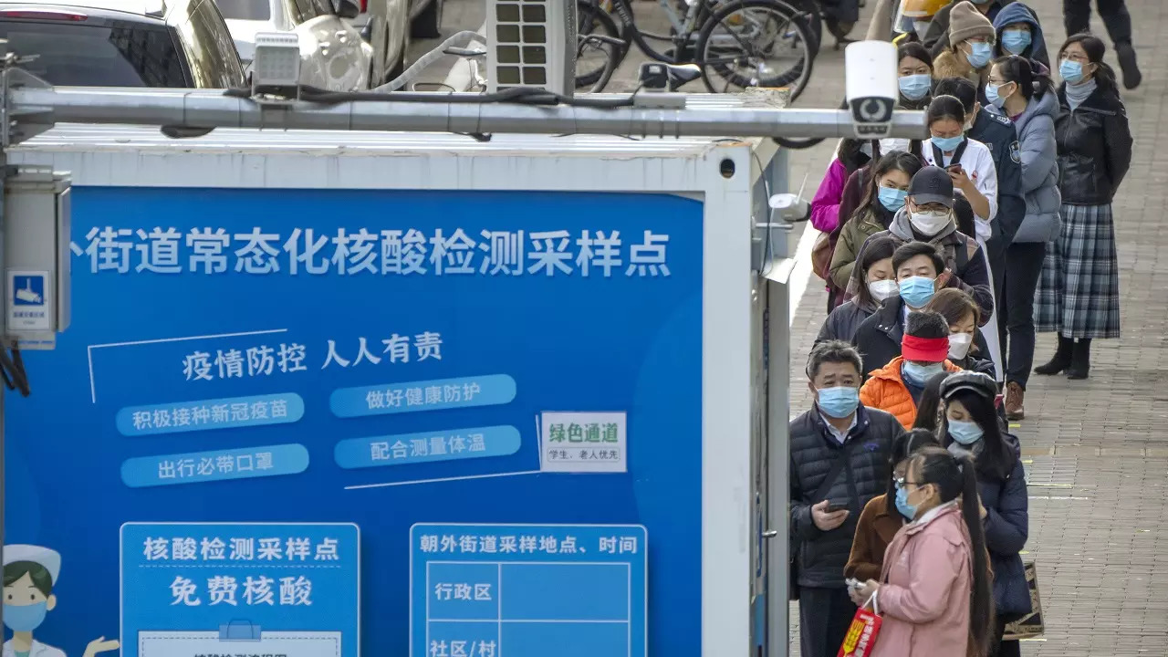 ​People wearing face masks stand in line for COVID-19 tests at a coronavirus testing site in Beijing​