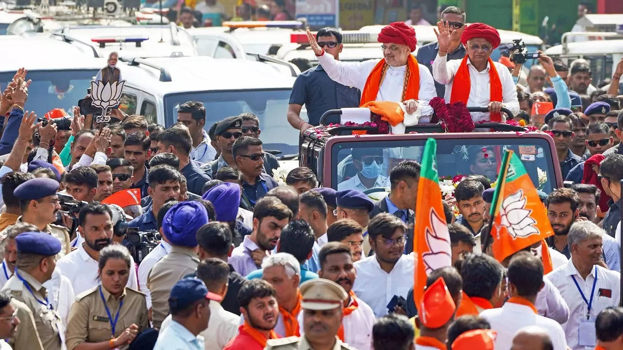 Union Home Minister Amit Shah and Gujarat CM Bhupendra Patel wave to the crowd during a roadshow before Patel files his nomination for the upcoming Gujarat assembly elections