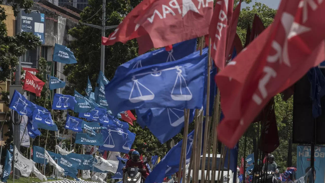 Motorcycles passing by campaign flags of Malaysia's ruling National Front coalition, or Barisan Nasional (blue) and Pakatan Harapan (Alliance of Hope) coalition (red) displayed in Kuala Lumpur