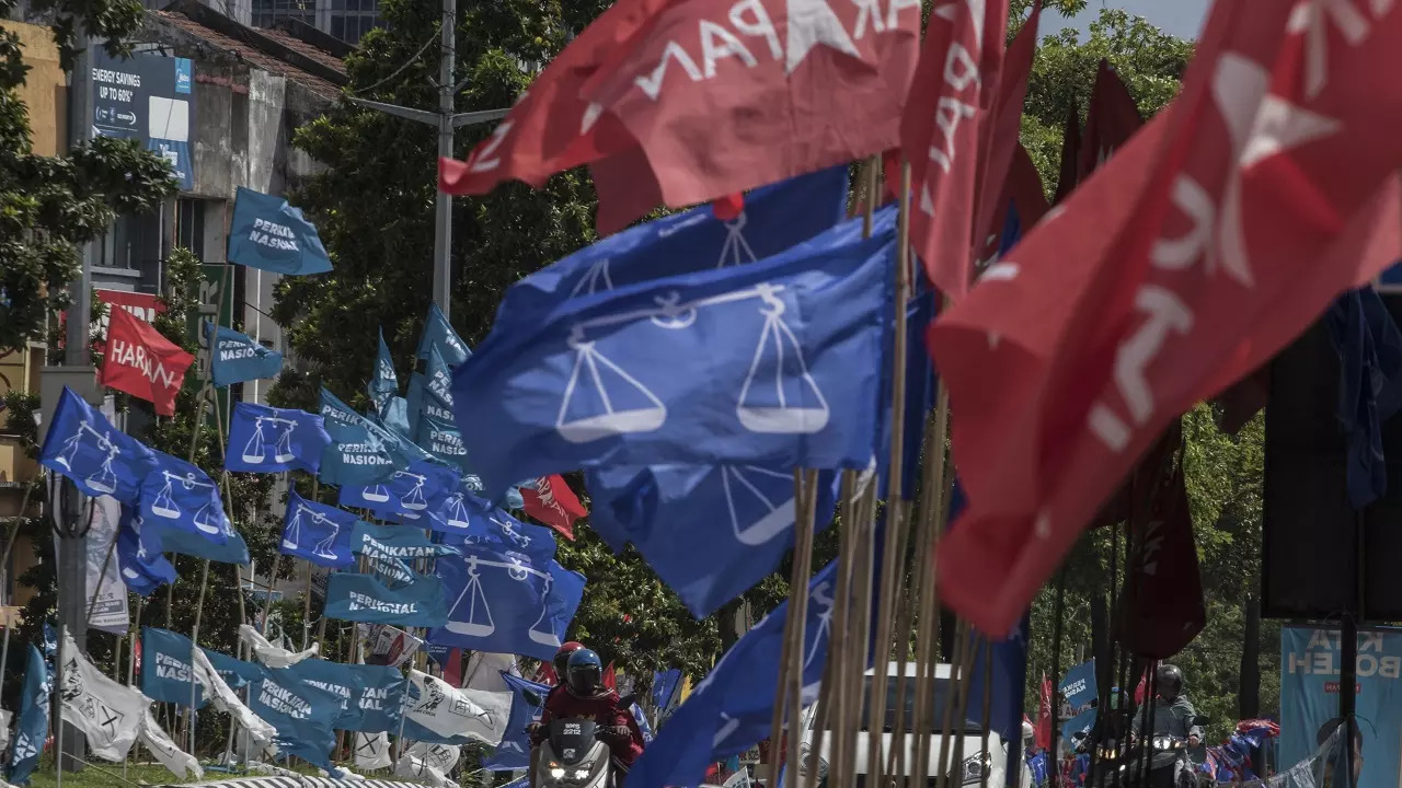 Motorcycles passing by campaign flags of Malaysia's ruling National Front coalition, or Barisan Nasional (blue) and Pakatan Harapan (Alliance of Hope) coalition (red) displayed in Kuala Lumpur