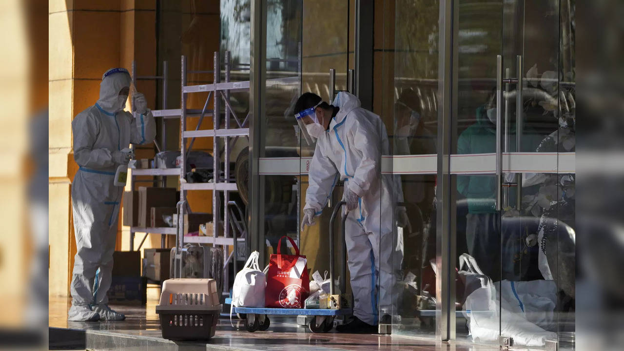 Workers in protective gear load goods on a trolley to transfer to the locked down residents in Beijing