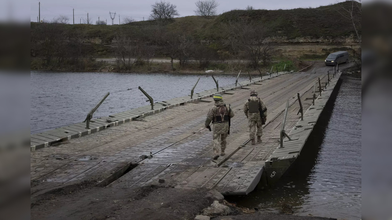 Ukrainian servicemen walk on a pontoon bridge across the Inhulets river in Kherson region