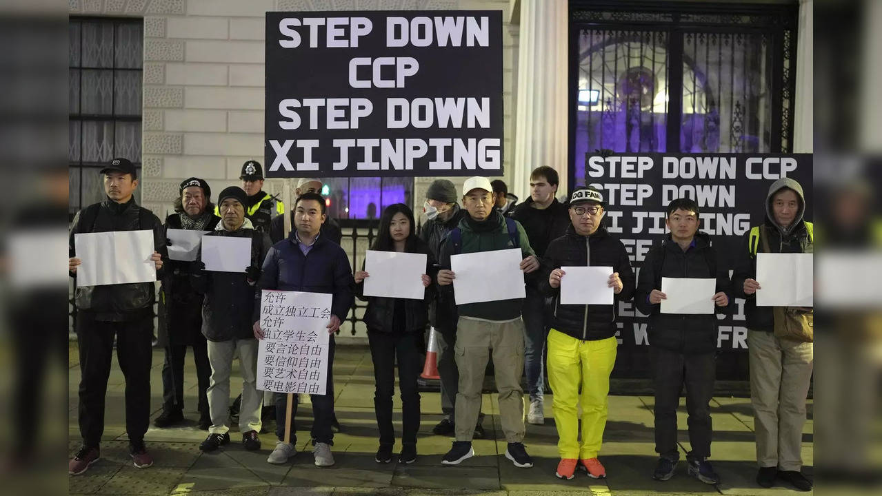 Protesters hold up blank papers and chant slogan as they gather outside the Chin...