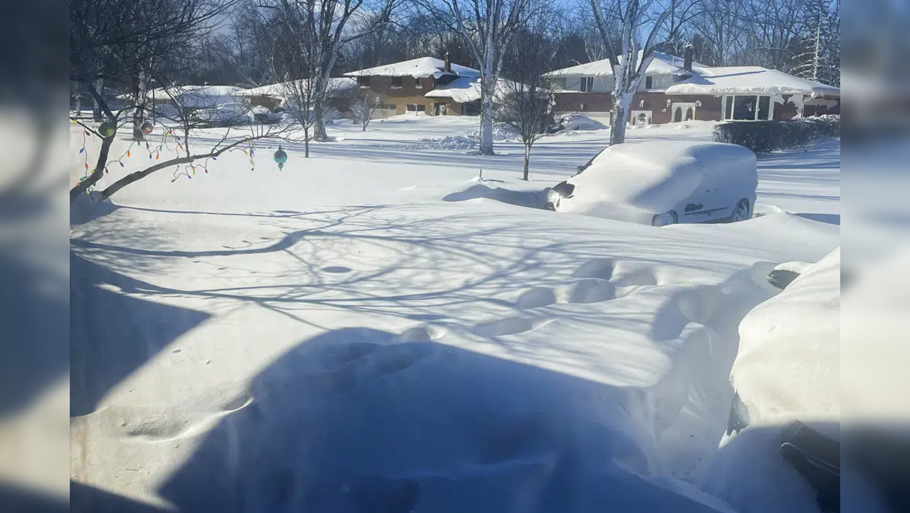 A car sits blanketed in snow on a driveway.