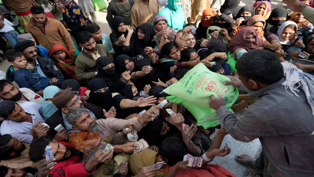 Pakistani people gather to buy subsidized sacks of flour from a sale point in Karachi, Pakistan, Sat