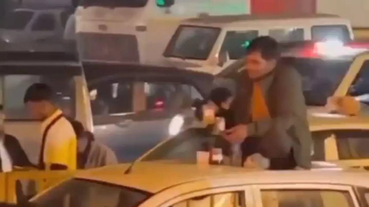 Man supposedly drinks alcohol while sitting on top of a car in the middle of a traffic jam in Gurgaon | Screengrab: Twitter